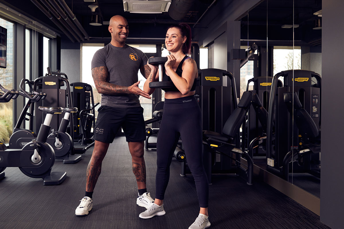 Ein Mann und eine Frau in einem Fitnessstudio halten Hanteln für ein effektives Training.