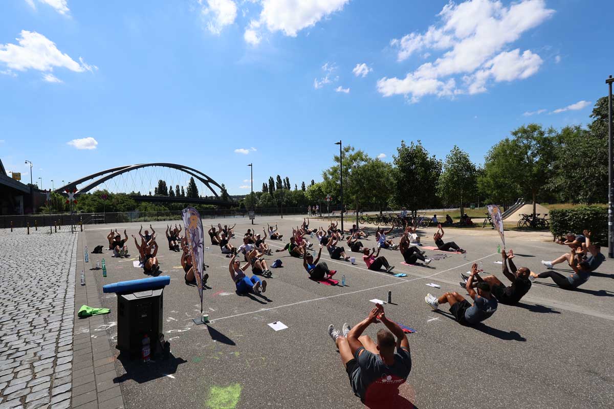 Eine Gruppe von Menschen genießt eine der besten Outdoor-Sportmöglichkeiten beim Yoga auf einem Parkplatz in Frankfurt am Main.